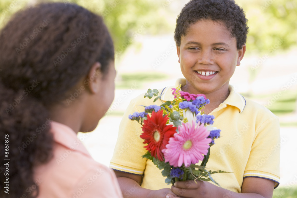 Young boy giving young girl flowers and smiling