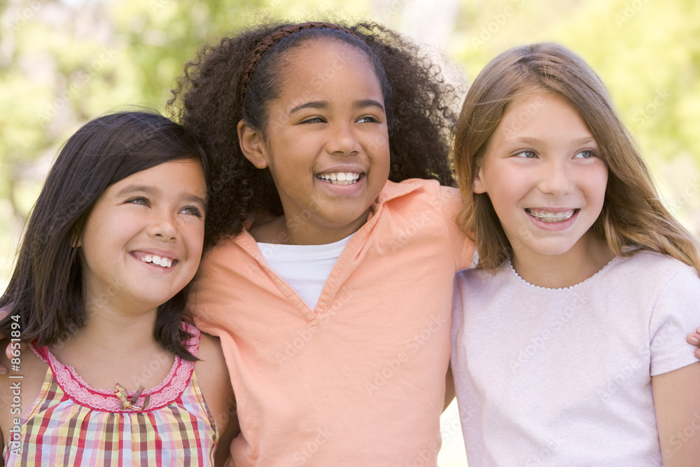 Three young girl friends outdoors smiling Three young girl friends outdoors smiling