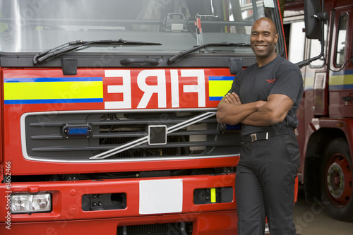 Portrait of a firefighter standing by a fire engine © Monkey Business