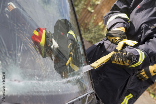 Firefighters breaking a car windscreen to help car crash victim