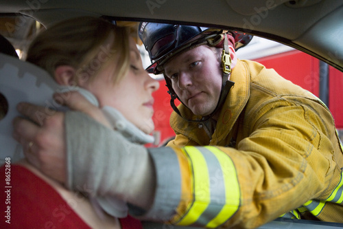 Firefighters helping an injured woman in a car photo