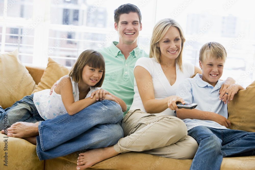 Family sitting in living room with remote control smiling Family sitting in living room with remote control smiling