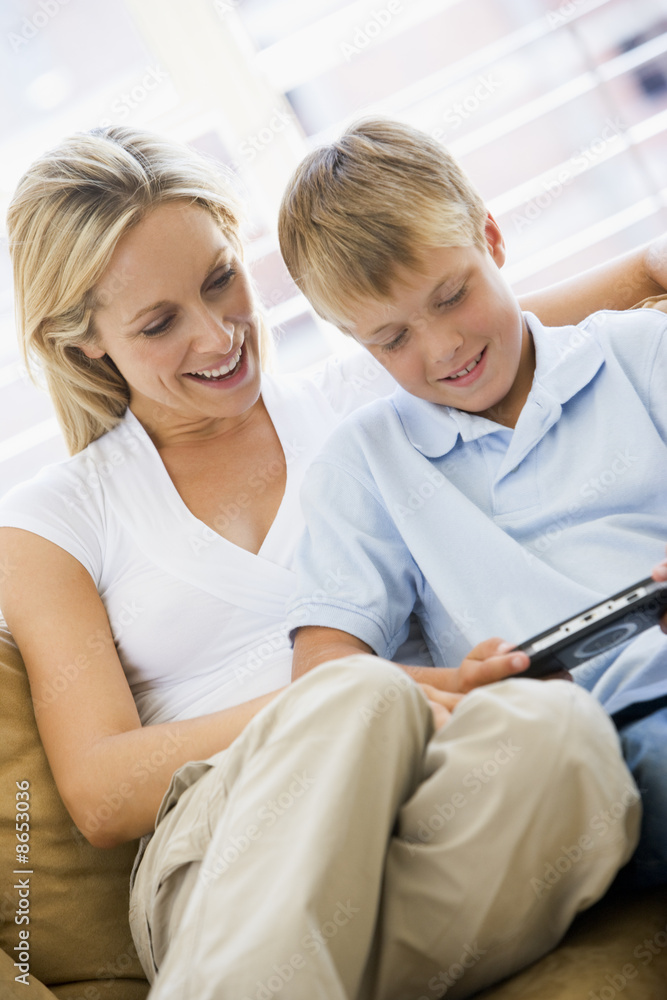 Woman and young boy in living room with handheld video game smil