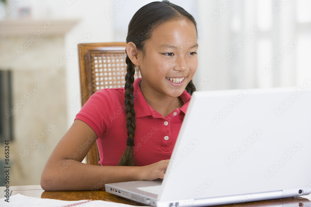 Young girl with laptop in dining room smiling Young girl with laptop in dining room smiling