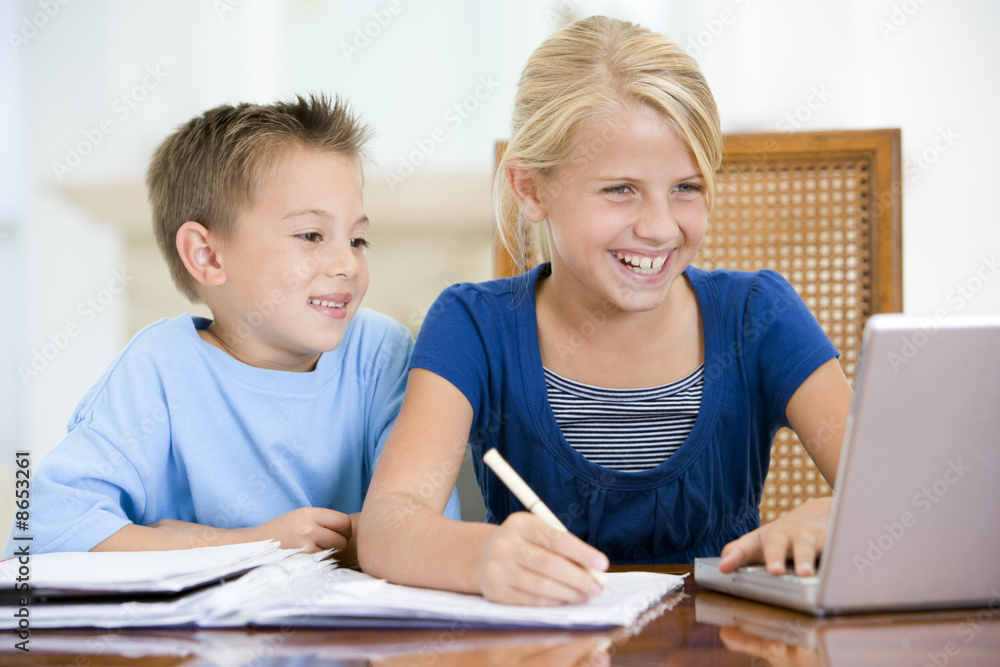 Two young children with laptop doing homework in dining room smi Two young children with laptop doing homework in dining room smi