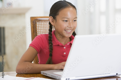 Young girl with laptop in dining room smiling © Monkey Business