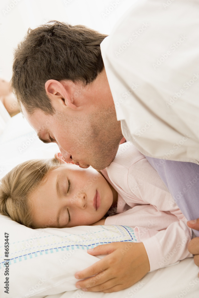 Man waking young girl in bed with kiss Man waking young girl in bed with kiss