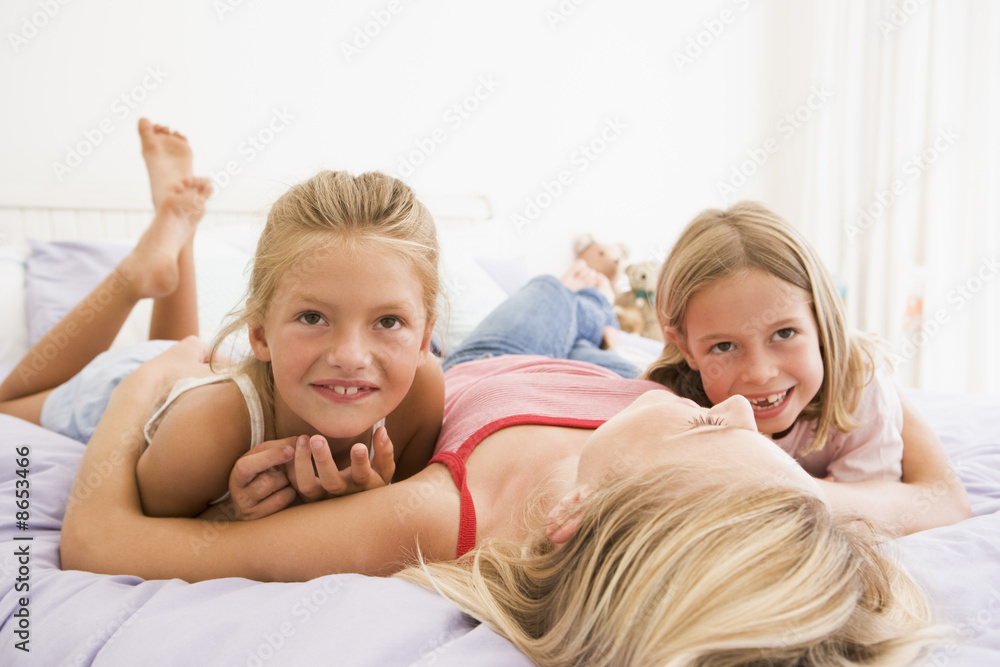 Woman lying in bed with two young girls smiling