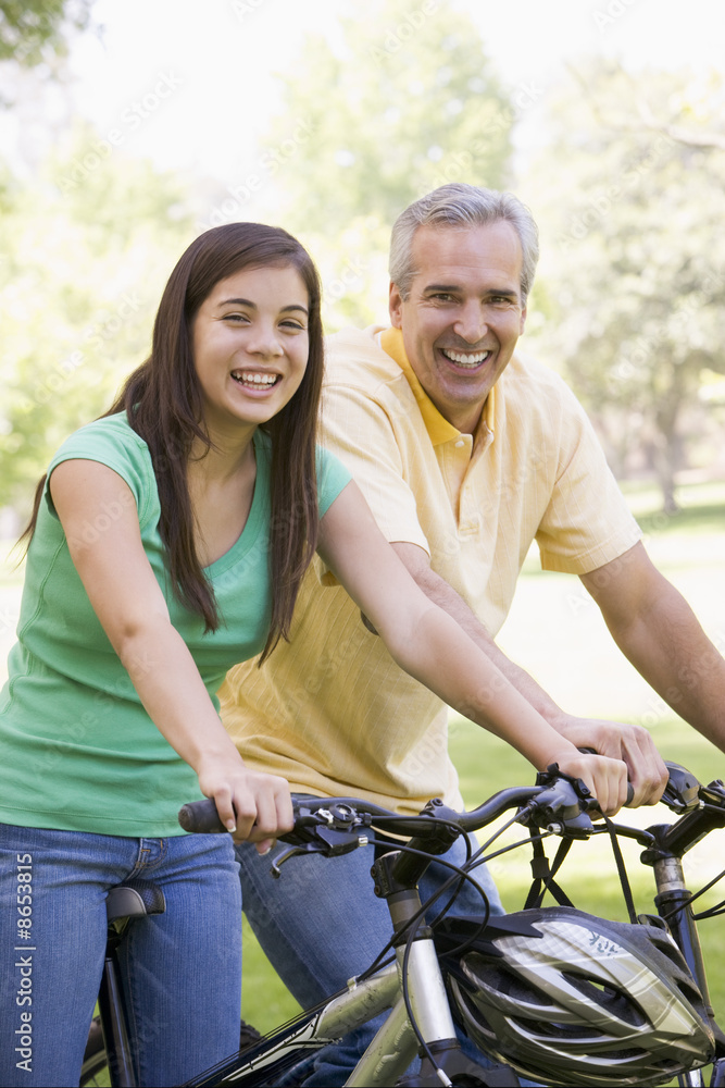 Obraz premium Man and girl on bikes outdoors smiling