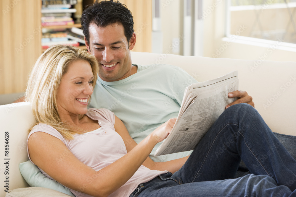 Couple in living room reading newspaper and smiling