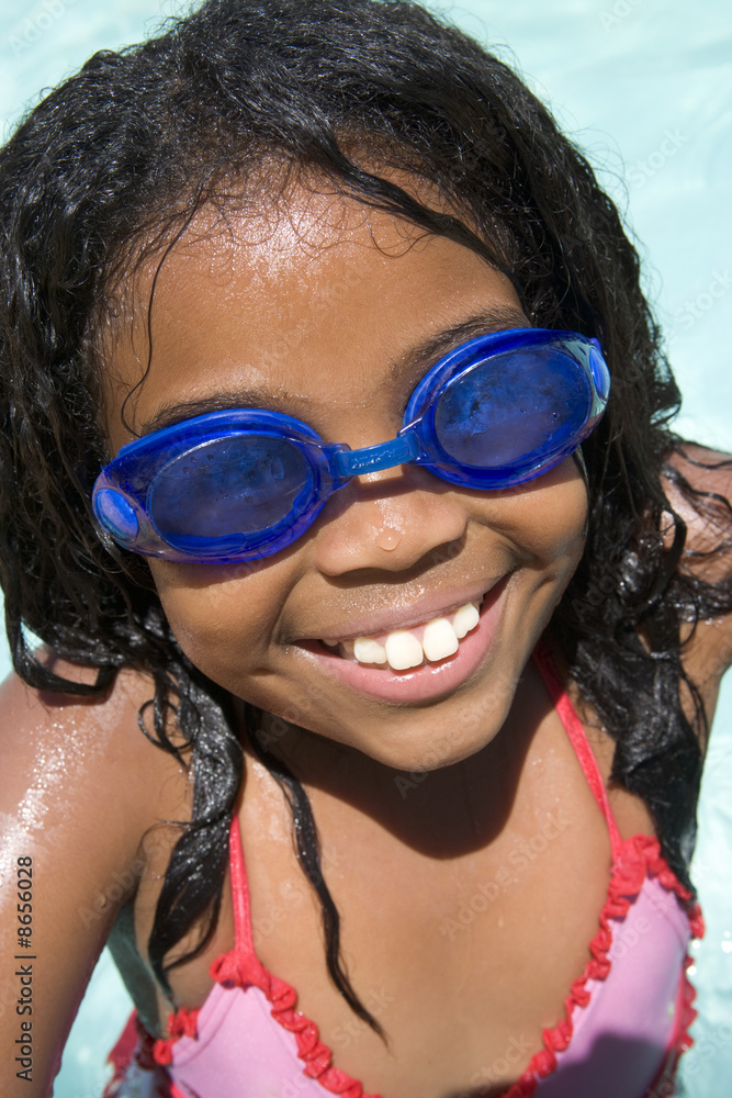 Young girl in swimming pool wearing goggles smiling