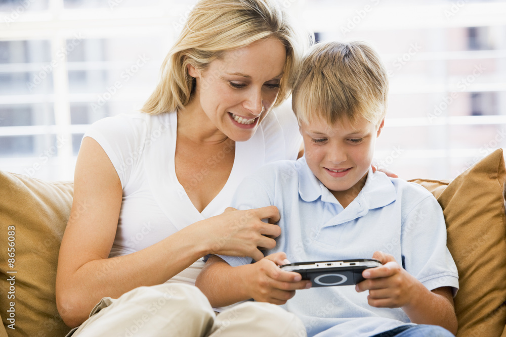 Woman and young boy in living room with handheld video game smil Woman and young boy in living room with handheld video game smil
