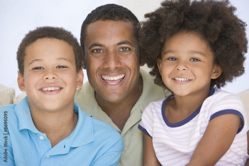Man and two young children sitting in living room smiling Man and two young children sitting in living room smiling