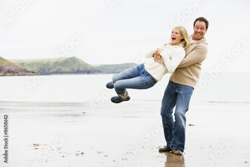 Couple playing on beach smiling