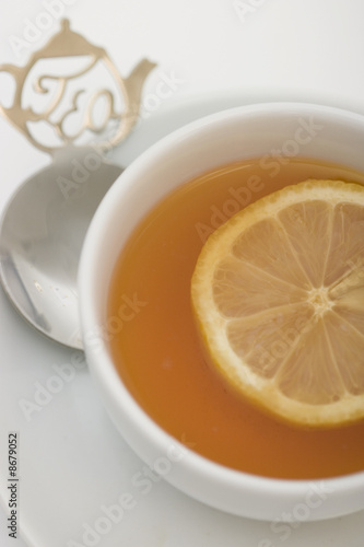 Tea serving in white cup with spoon and lemon slice