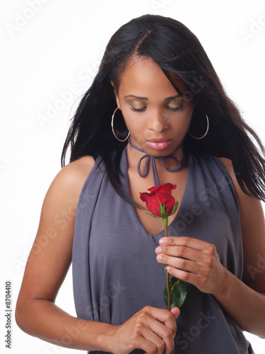 Young black woman looking down at red rose