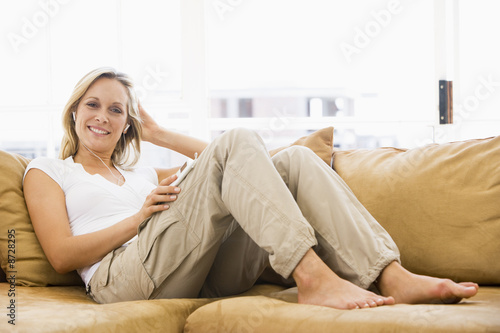 Woman in living room listening to MP3 player smiling