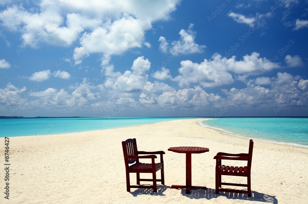 Two chairs and one table are on a beach