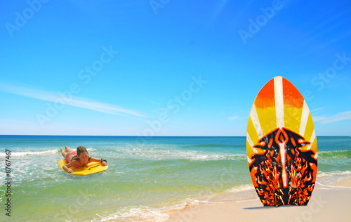 Sticker Girl body surfing towards board at beach