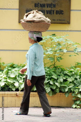 woman carrying a basket of fruit in hanoi