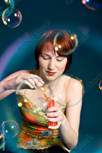Red haired girl is trying to blow some big bubbles