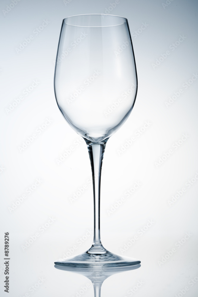 Empty wine glass on reflective surface over light background Empty wine glass on reflective surface over light background