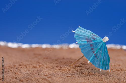 parasol on beach sand with sea and blue sky background © Elena Moiseeva