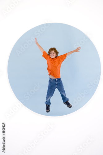 Young boy jumping with arms out smiling