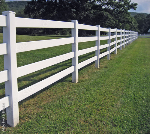 A long white fence on a mountain ranch.