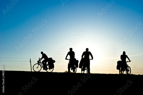 Group of Bicycle tourists on a road against sunset