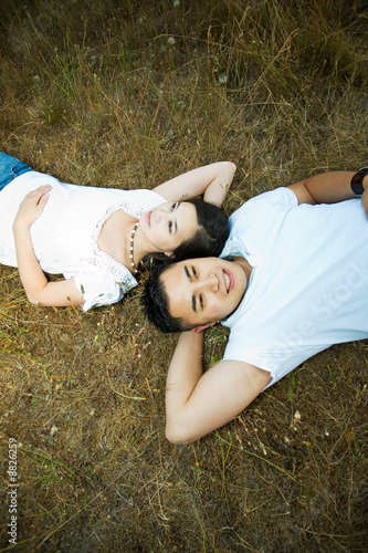 A shot of an asian couple lying down on the grass
