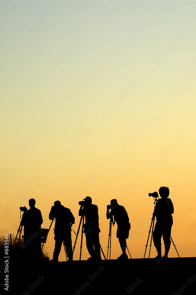 Silouette of five photographers lined up shooting photos