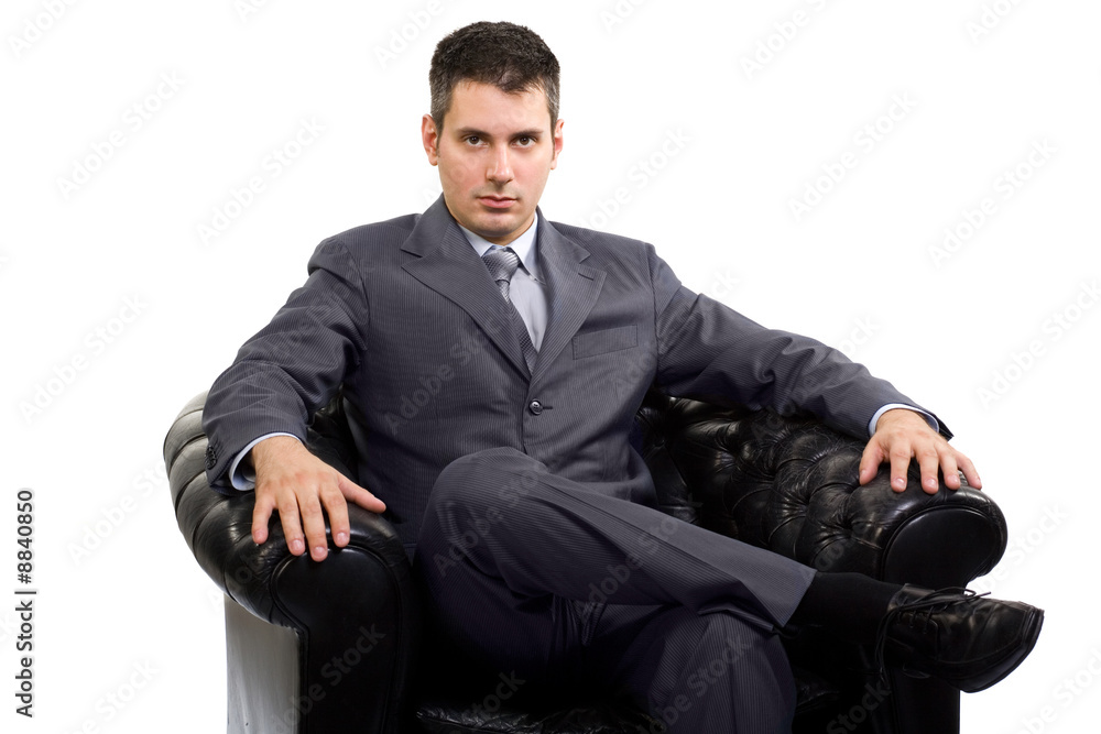 Young caucasian businessman in a suite, sitting in armchair