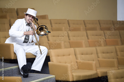 A trombonist in a white suit and yellow background.