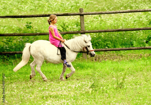 Little girl in pink dress galloping on her white pony © Capricornfoto