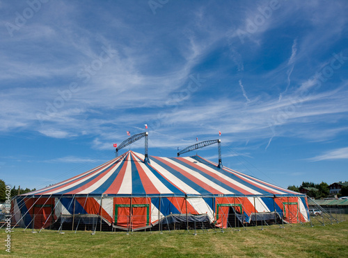 Le chapiteau bleu blanc rouge d'un cirque installé dans un champ photo