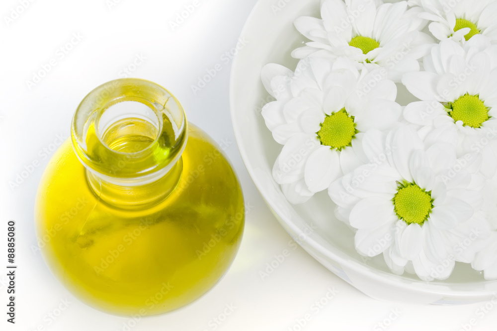 body oil and beautiful white daisies floating in a bowl of water body oil and beautiful white daisies floating in a bowl of water