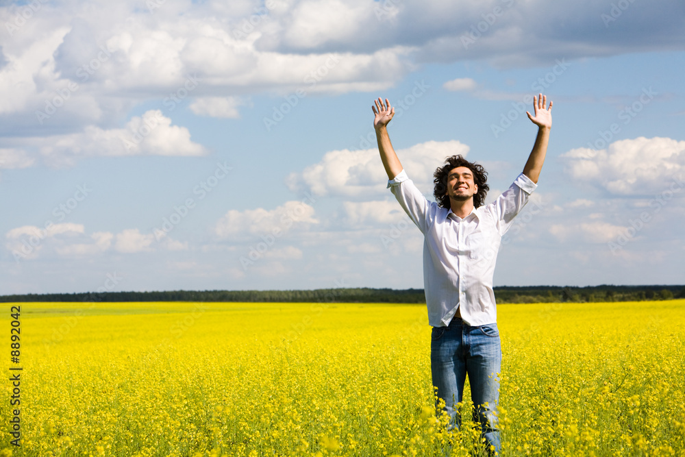 View of smiling man raising his hands standing in the field View of smiling man raising his hands standing in the field