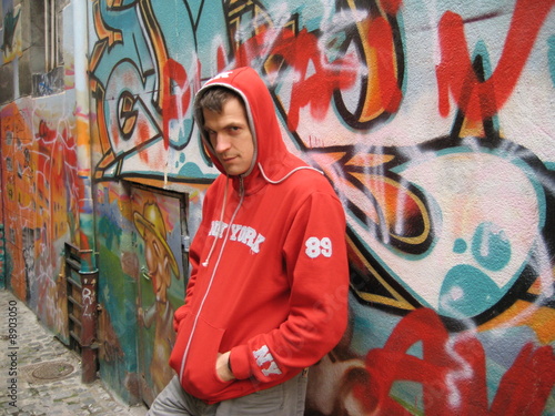 Man with a hood by Graffiti wall