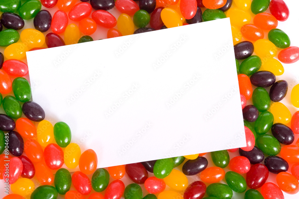 A white blank note-card surrounded by multi-color jelly beans A white blank note-card surrounded by multi-color jelly beans