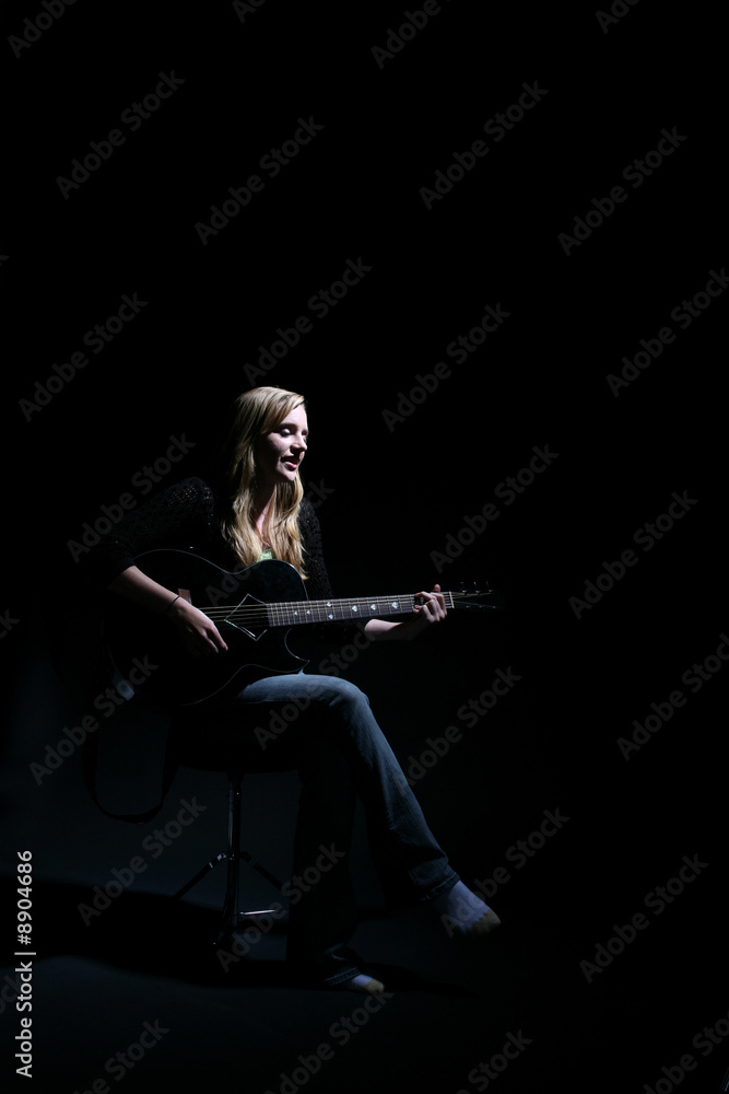 Fototapeta premium woman on dark stage performing with the guitar