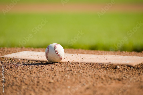 A white leather baseball lying on top of the pitcher's mound