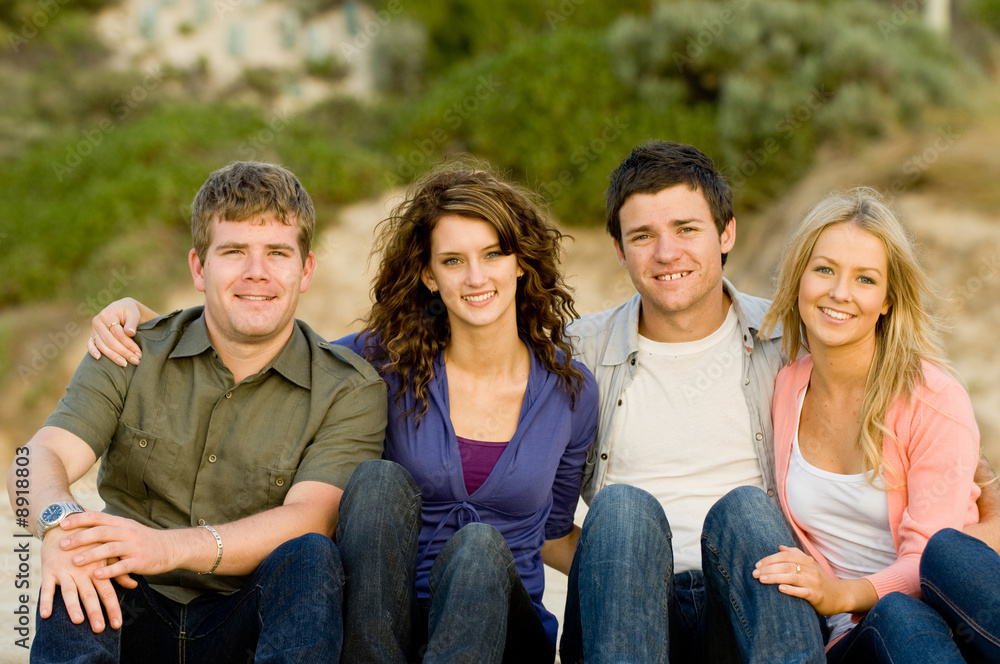Fototapeta premium Four friends sitting together at the beach