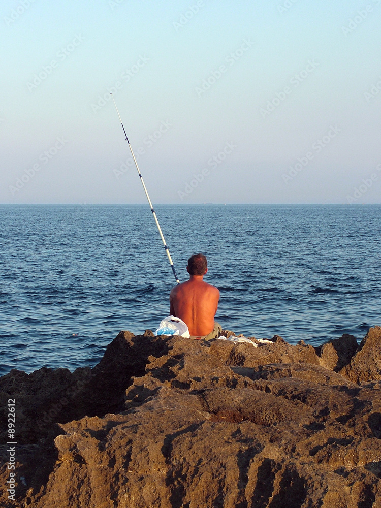 pescatore sullo sconglio in riva al mare