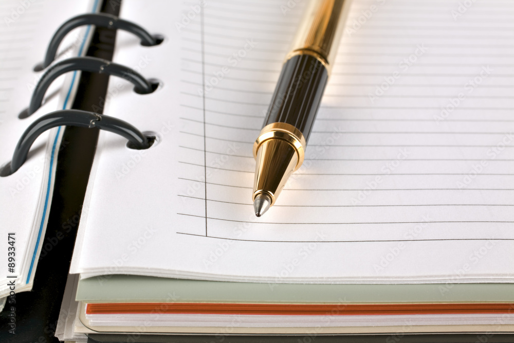 Ballpoint pen resting on notebook over a white background Ballpoint pen resting on notebook over a white background