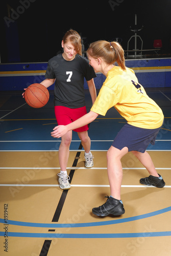 Two female basketball players compete in gym