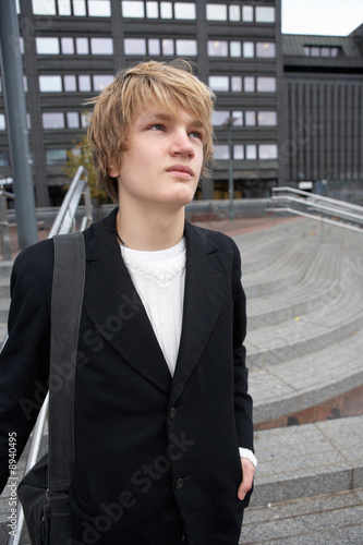 Portrait of teenage boy in city, carrying shoulder bag