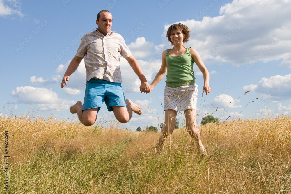 happy couple jumping together on a summer day happy couple jumping together on a summer day