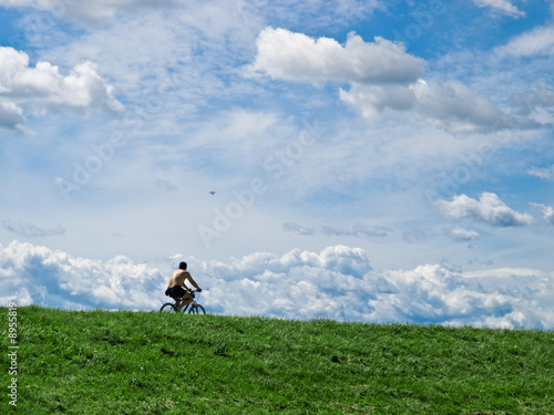 cyclist in the nature against blue sky and green grass in front