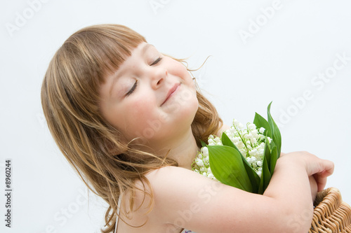 little, pretty girl holding bunch of lilies of the valley
